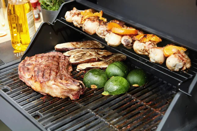 Gasbarbecue met gegrilde steak, kipspiesjes en courgettes op grillroosters