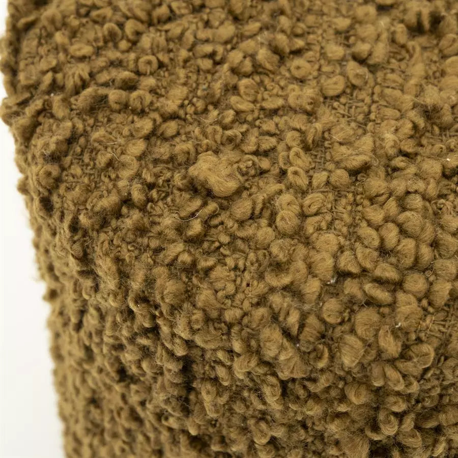 Bouclé stofdetail van mosterdgele poef met krullende textuur.