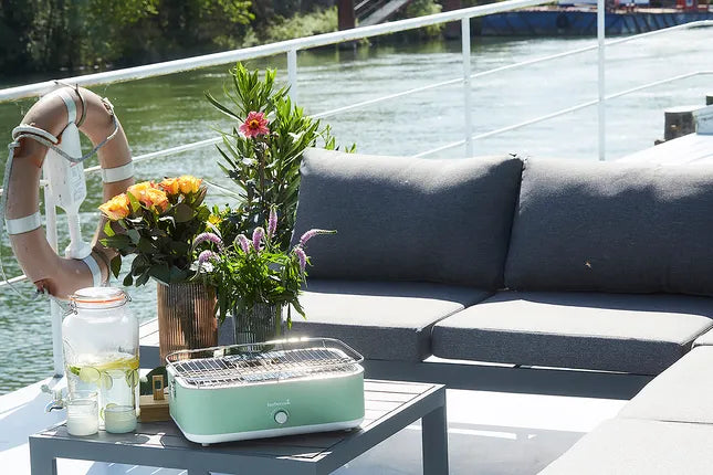 Groene elektrische tafelgrill op terras met rooster en deksel