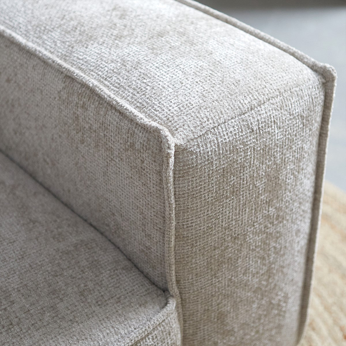 Lichtgrijze bankarmleuning met fijne geweven stofstructuur