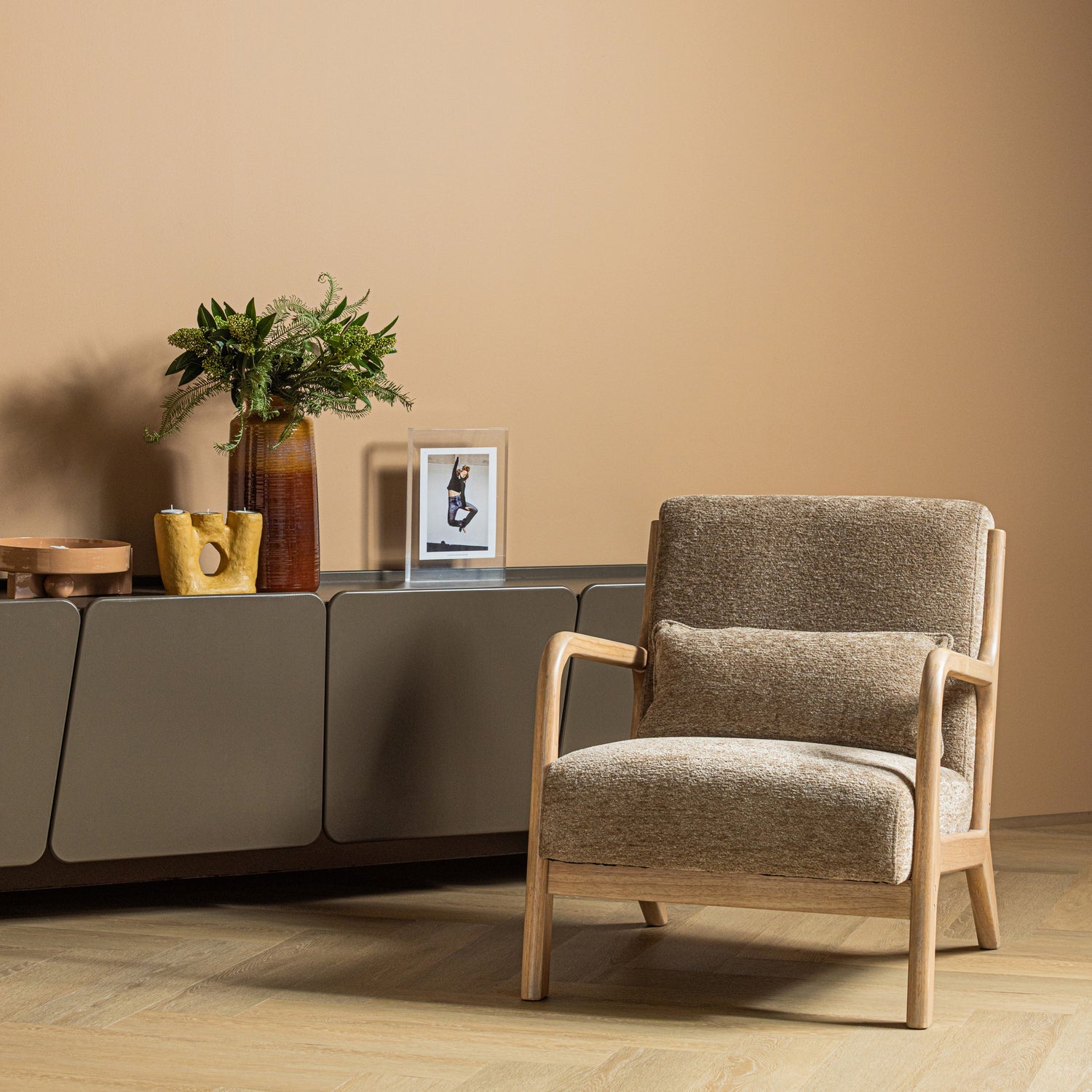 Zandkleurige chenille fauteuil met houten frame en armleuningen.