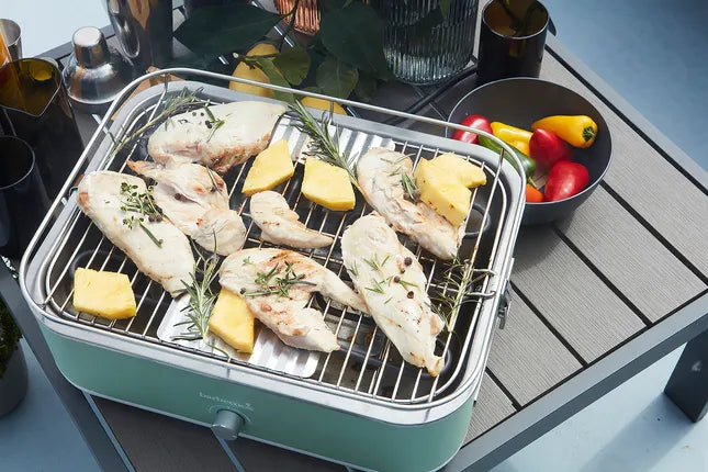 Groene elektrische tafelgrill met kip, kaas en kruiden op het rooster