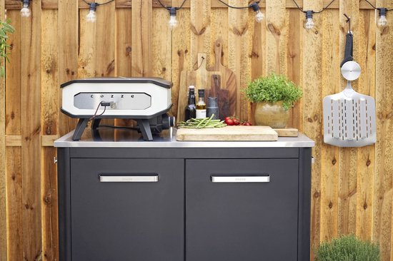 Elektrische pizzaoven op buitenkeukenmeubel, wit ombouw en zwarte basis.