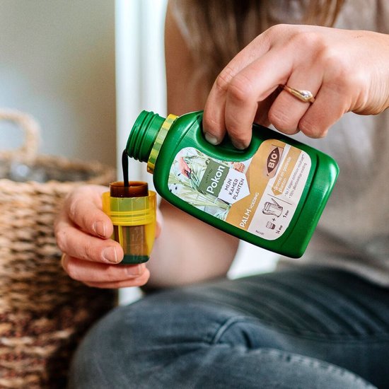Palmvoeding fles met geleksel; hand giet vloeistof in kleine pot