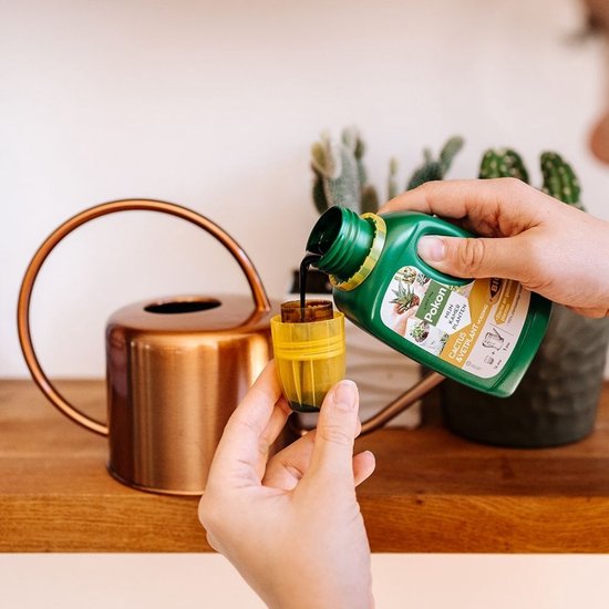 Cactus- en vetplantvoeding flesje met gele dop; hand draait de dop eraf