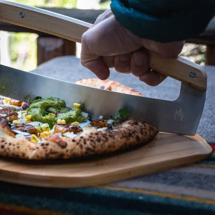 Pizza snijblad met houten handgreep onder pizza op grill