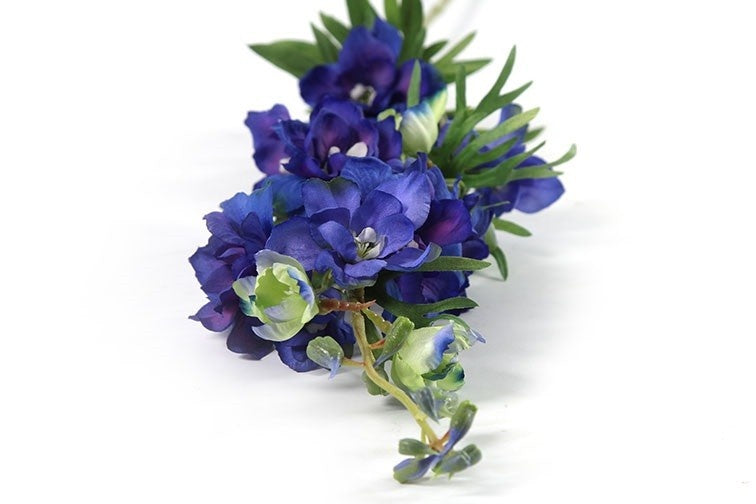 Blauw en paars delphinium boeket met kleine bloemen en groene bladeren.