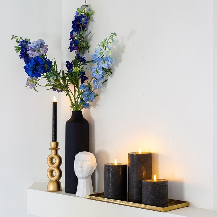 Blauw delphinium bloemenboeket in donkere vaas met groene stelen.