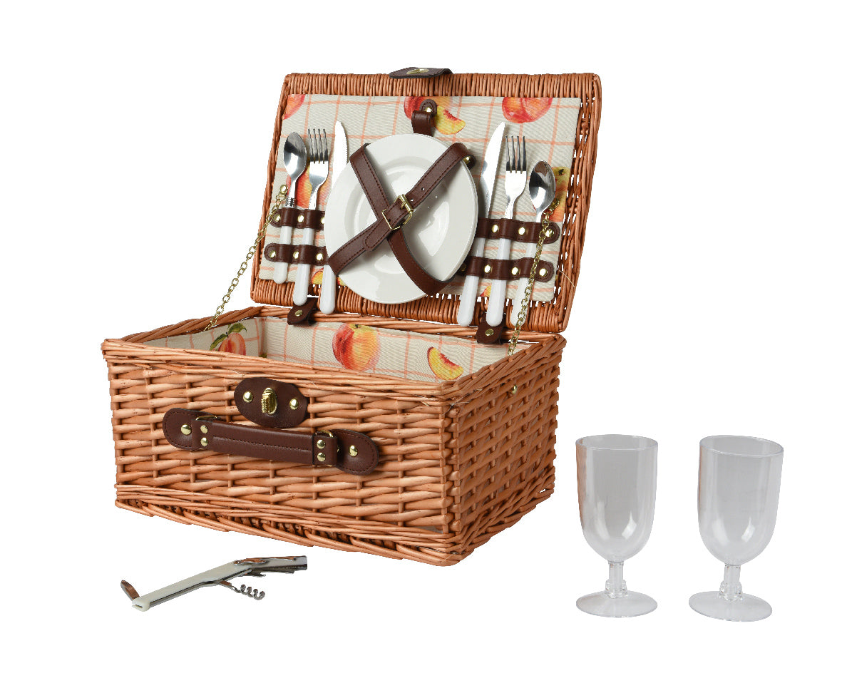 Rieten picknickmand met open deksel, bestek, borden en twee glazen