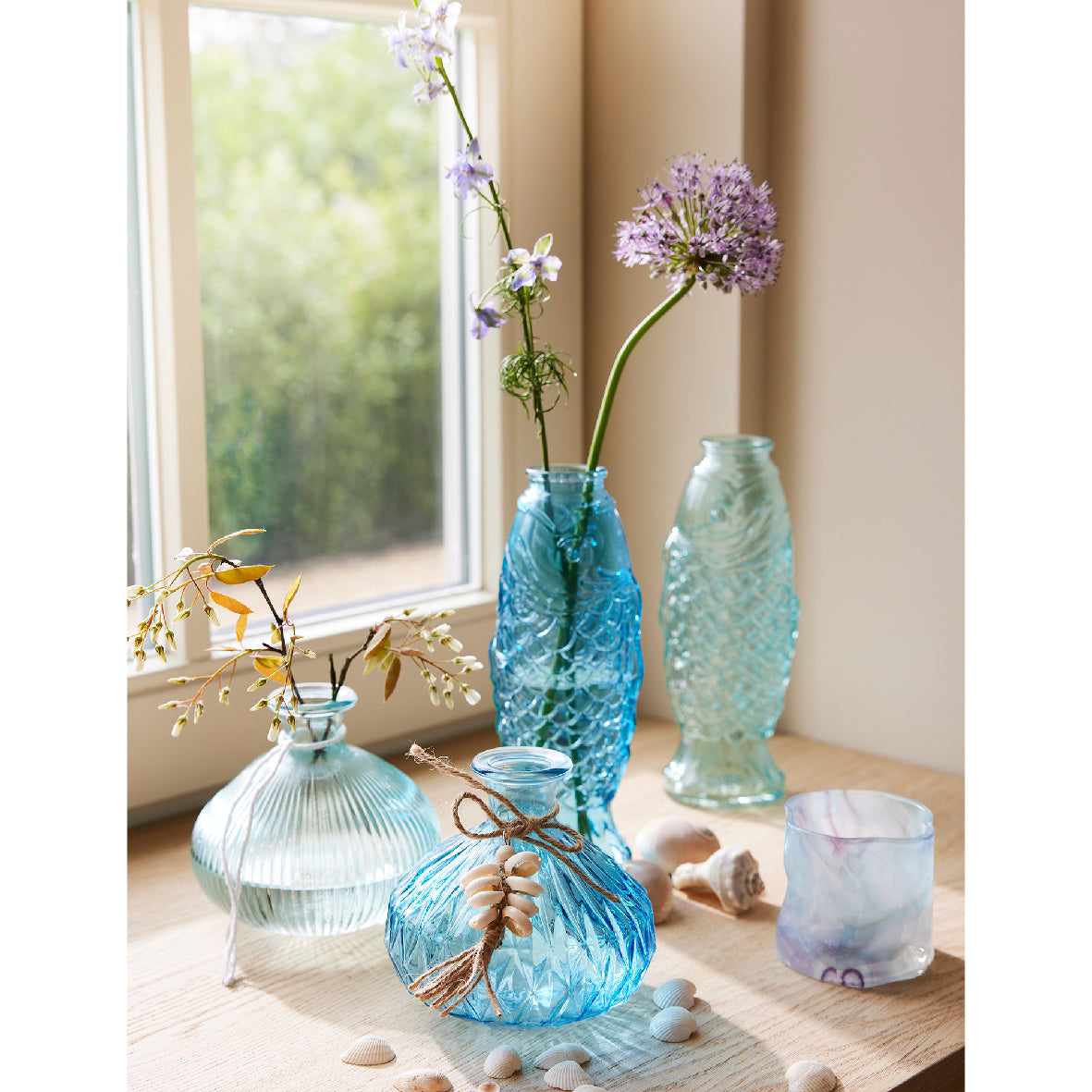 Assortiment blauwe glazen vazen met reliëf, op tafel met bloemen