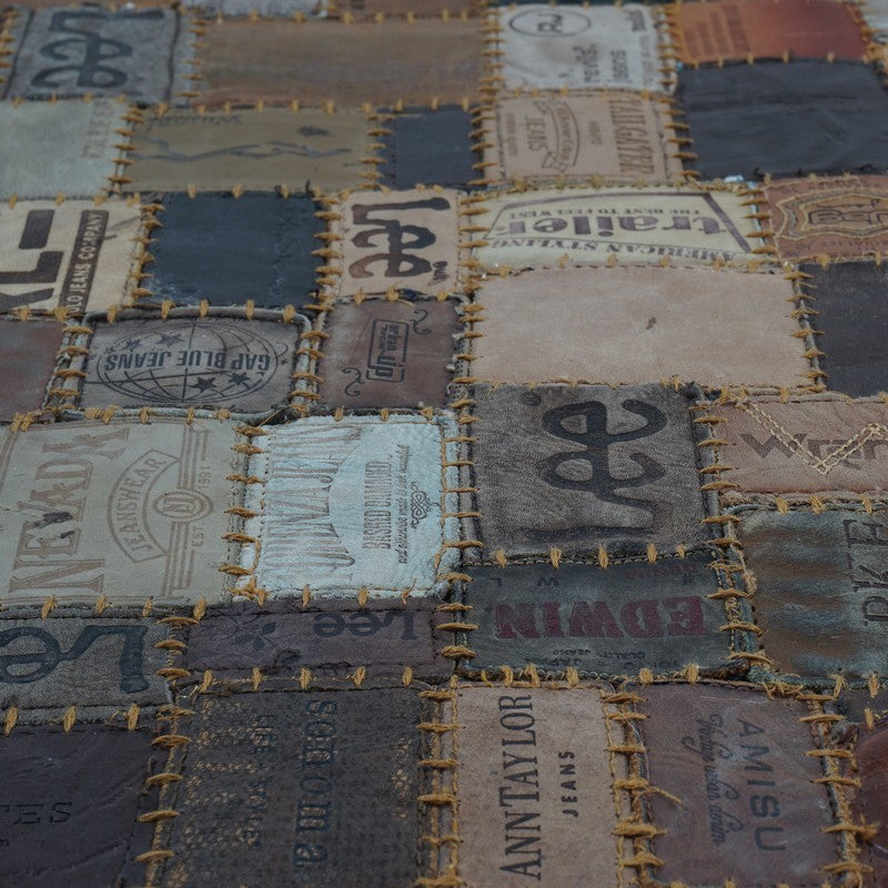 Patchwork karpetdetail met blauwe en beige vlakken, met gele stikrand