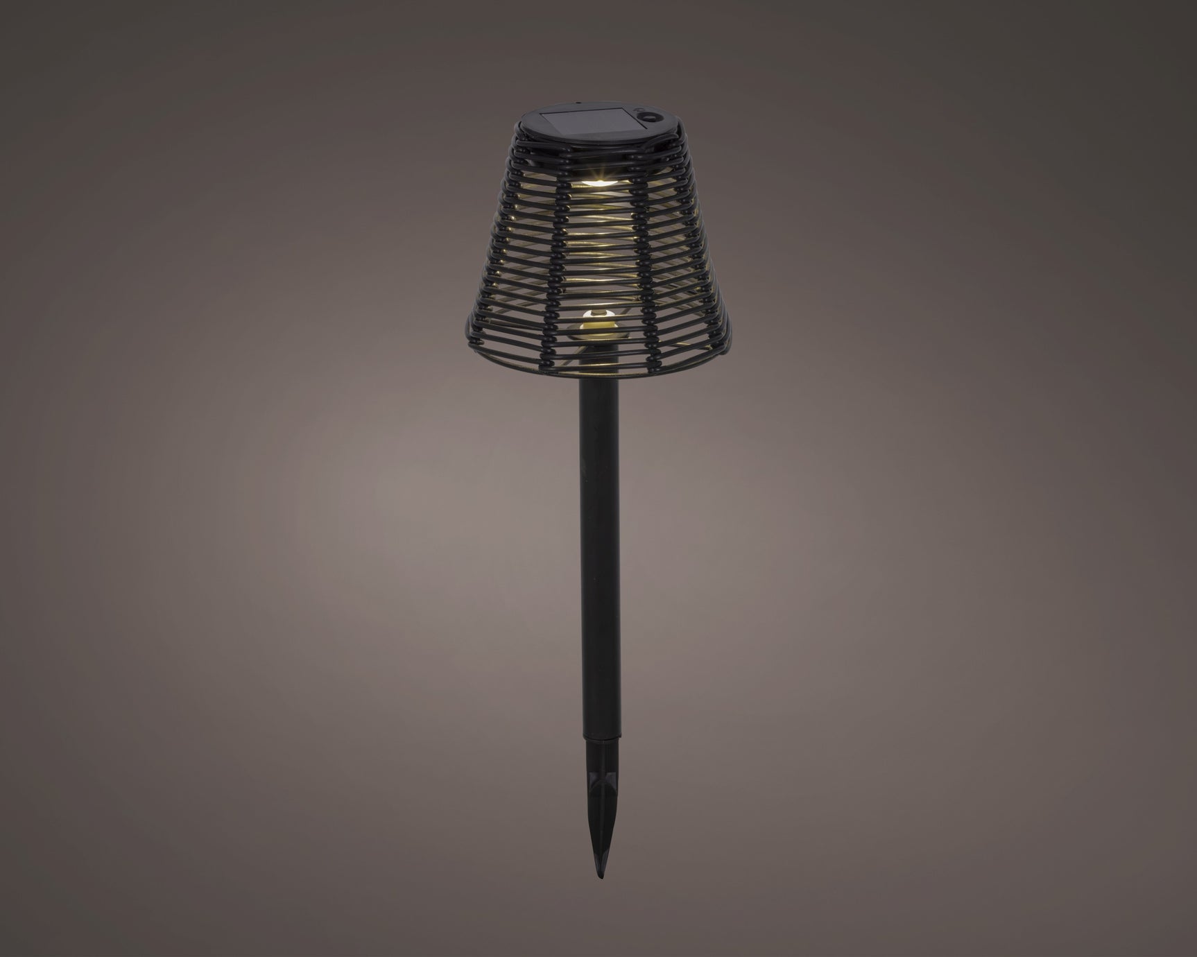 Zwarte zonne-tuinlamp met rieten kap en warme gloed, grondpin