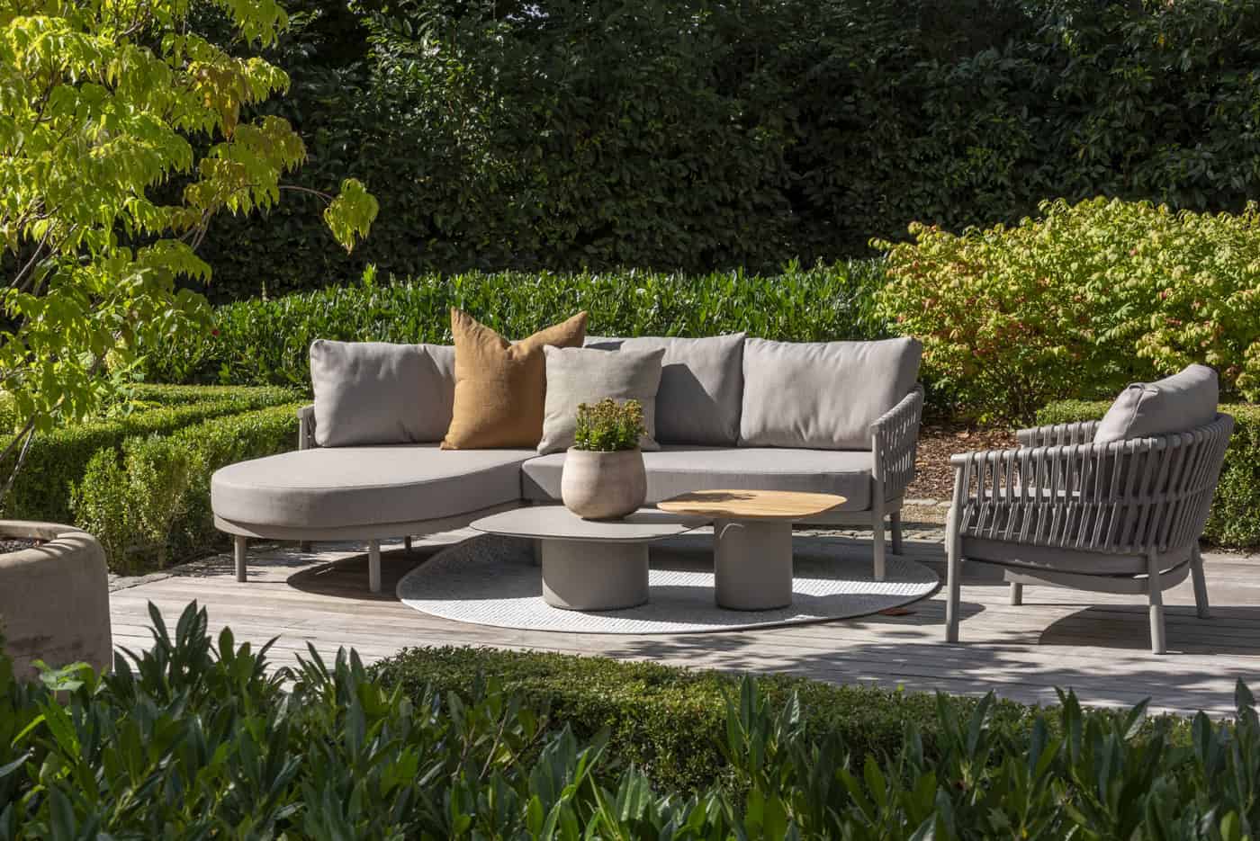 Twee ronde salontafels met houtlook blad en grijze voet in de tuin