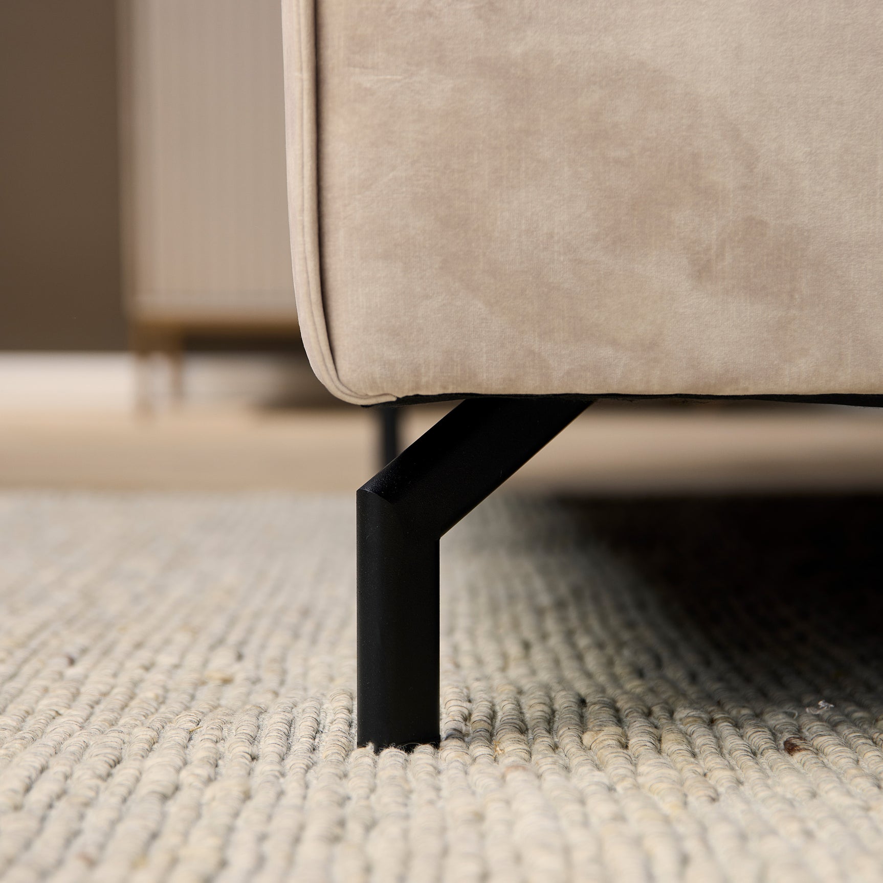 Loungebank met lichtgrijze bekleding en zwarte poot, zichtbare stofzoom onderaan