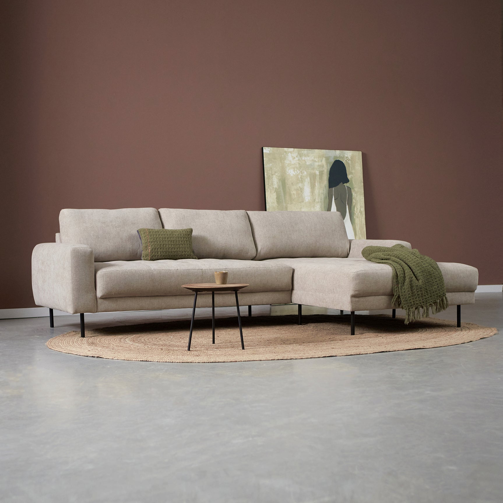 Bank met chaise longue rechts, lichtgrijs gestoffeerd, met kussens en groene plaid