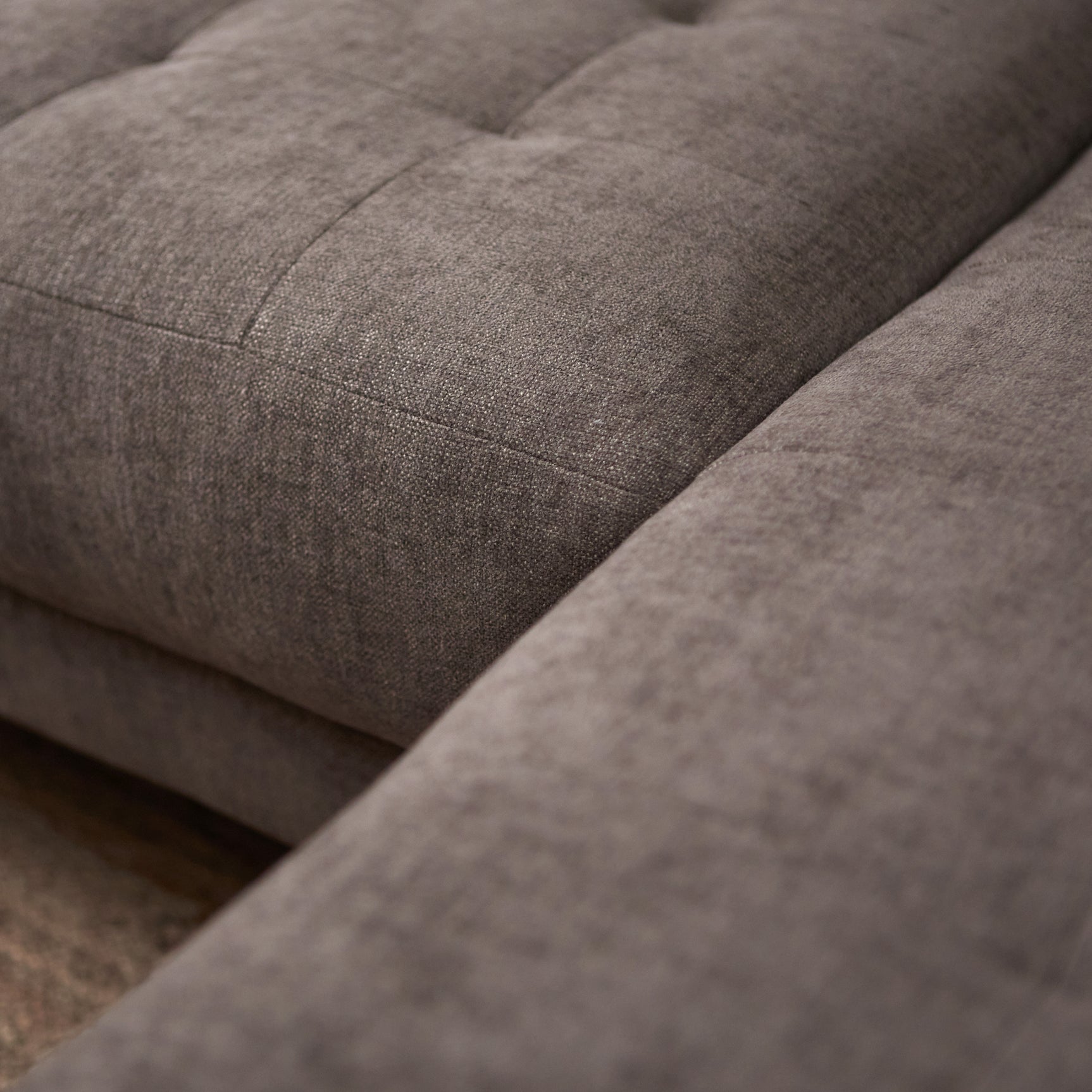 Bankzitting met grijze stoffering en stiksels, chaise deel in close-up