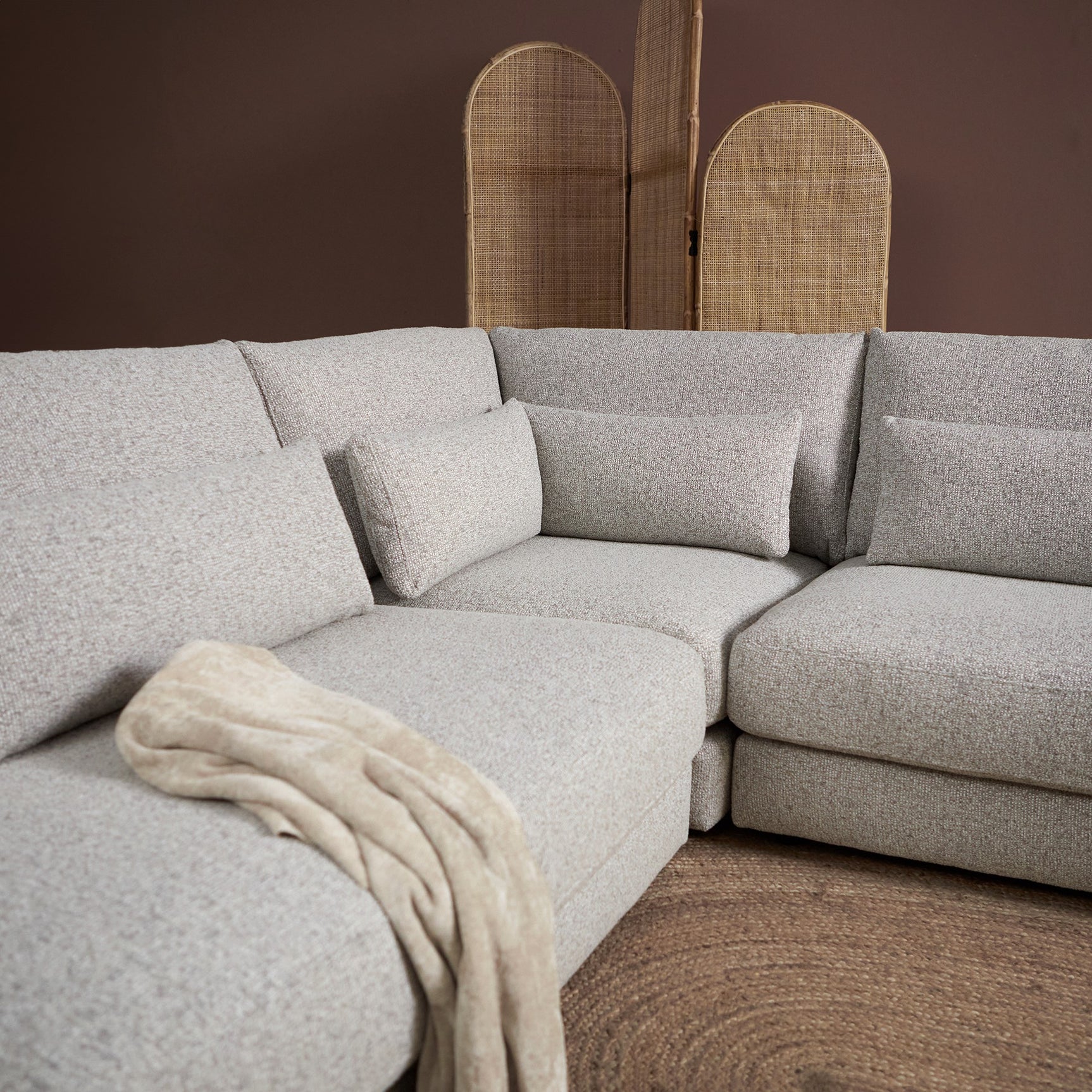 Chaise links met lichtgrijze loungebank, plaid over de zitting en hoge rugkussens
