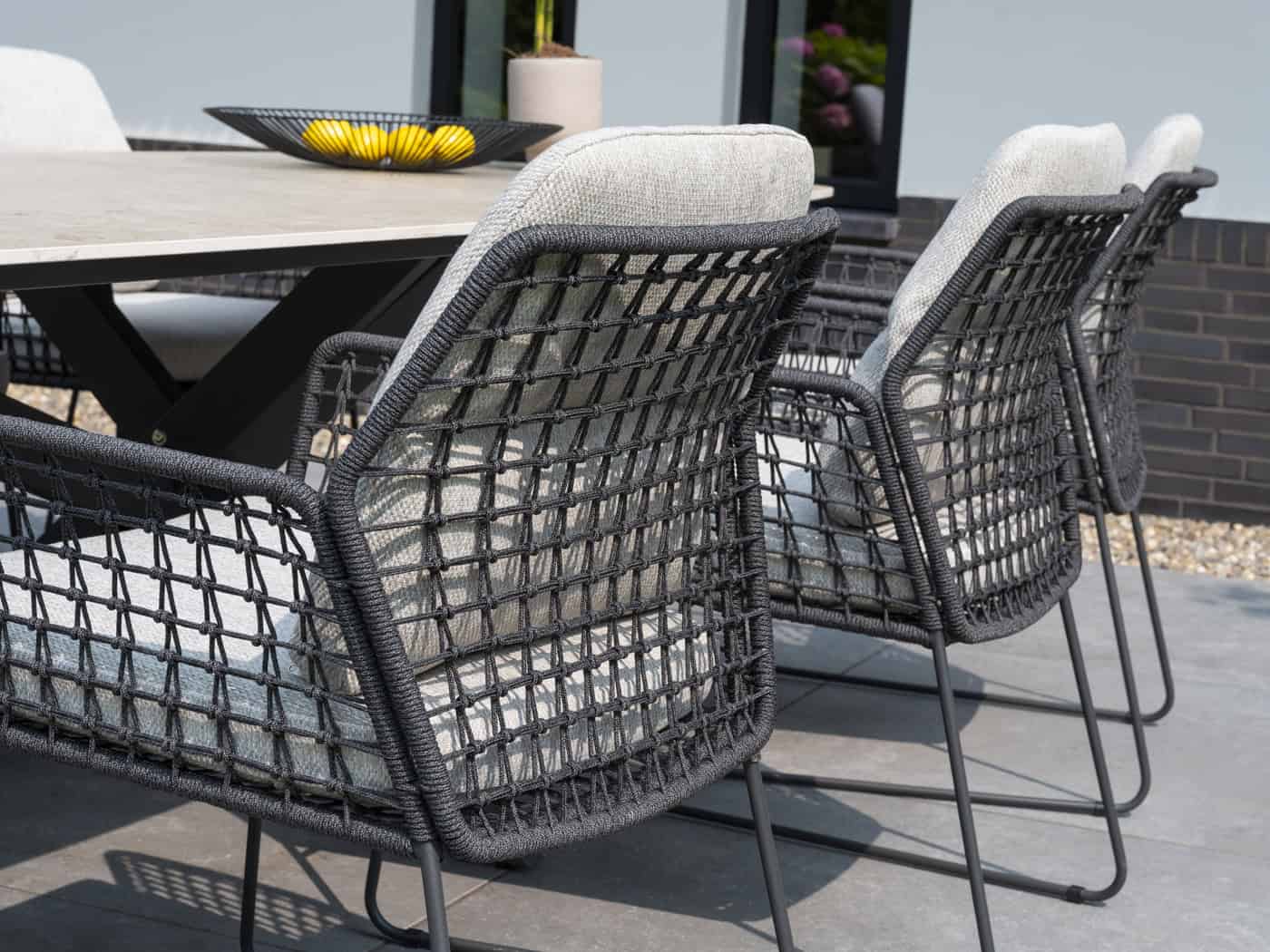Set diningstoelen met lichtbeige kussens en zwart draadframe, armleuningen en hoge rug