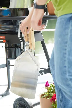 Pizzaspatel met houten greep en RVS schepblad, opgetild bij de barbecue