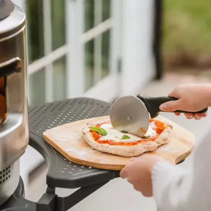 Pizzasnijder met metalen wieltje, snijdt pizza op houten plank