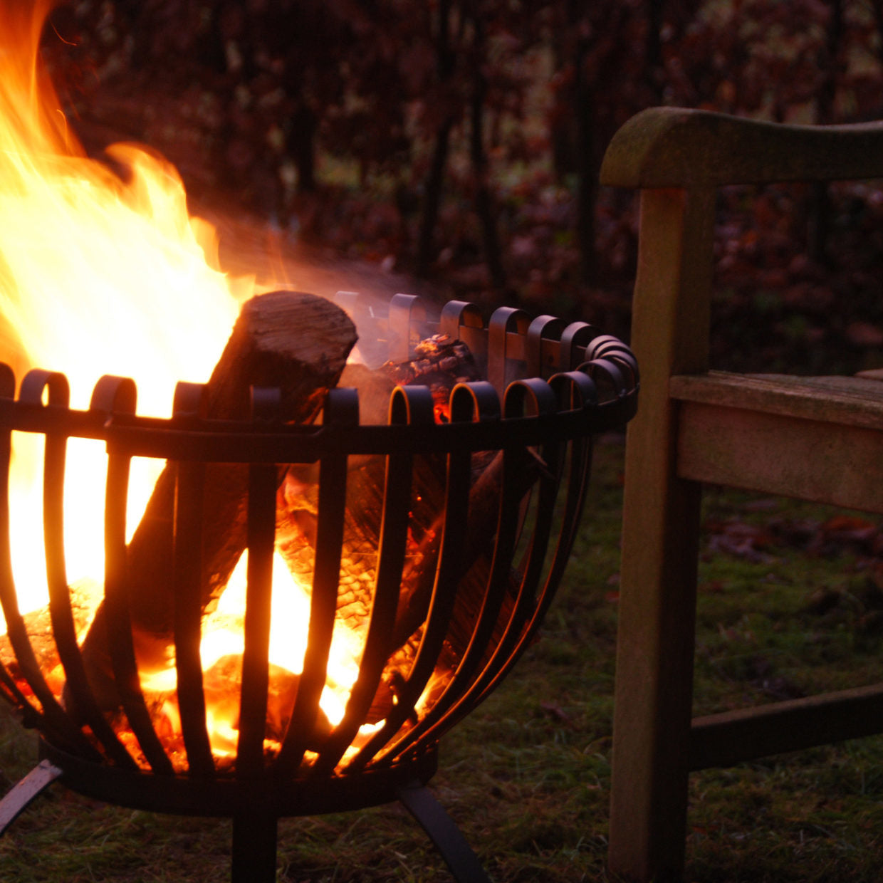 Tulpvormige vuurkorf met brandende vlammen, zwarte spijlen en houtblokken