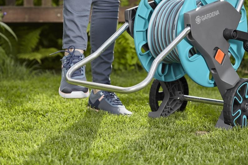 Gardena slangenwagen op gras, turkoois haspel met grijze slangklem en oranje detail