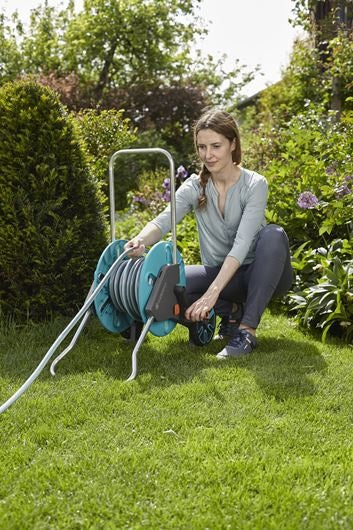 Gardena slangenwagen met haspel op gras, turkoois en grijs, duwbeugel en wielen