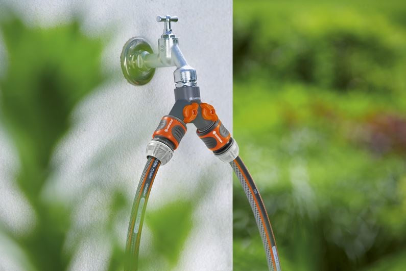 Gardena 2-wegstuk 3/4" met oranje bediening en twee uitgangen, slangen aangesloten