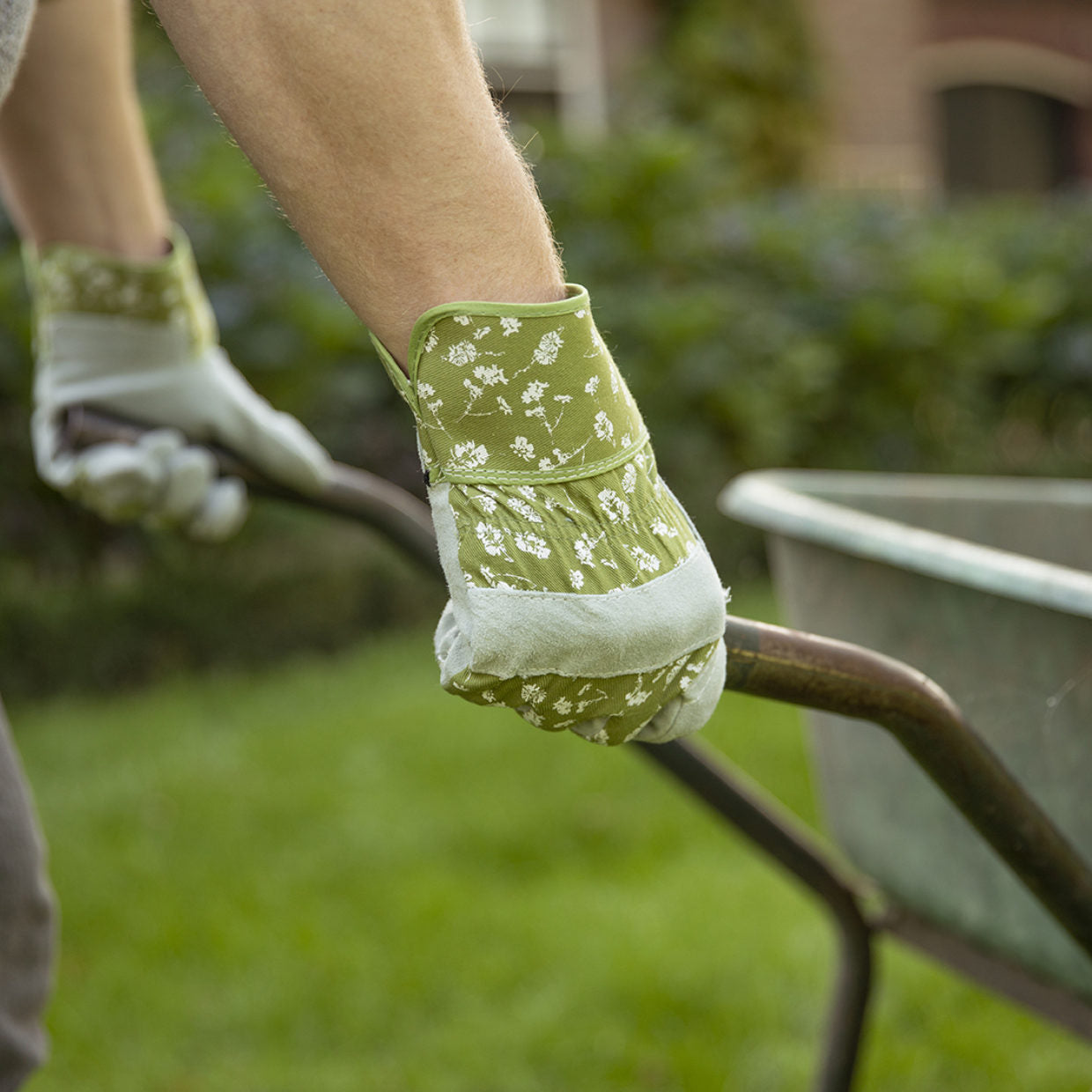 Werkhandschoen groen met wit bloemenpatroon aan hand bij tuinwerktuig