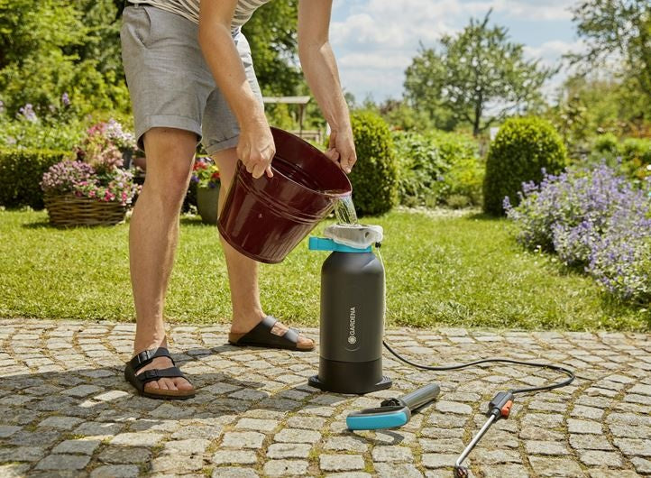 Gardena drukspuit 5 l met zwarte tank en turquoise bovenrand, in tuinopstelling
