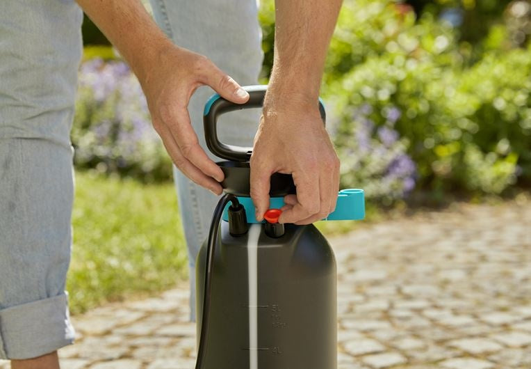Gardena drukspuit 5 l: handen op zwarte handgreep met turquoise hendel