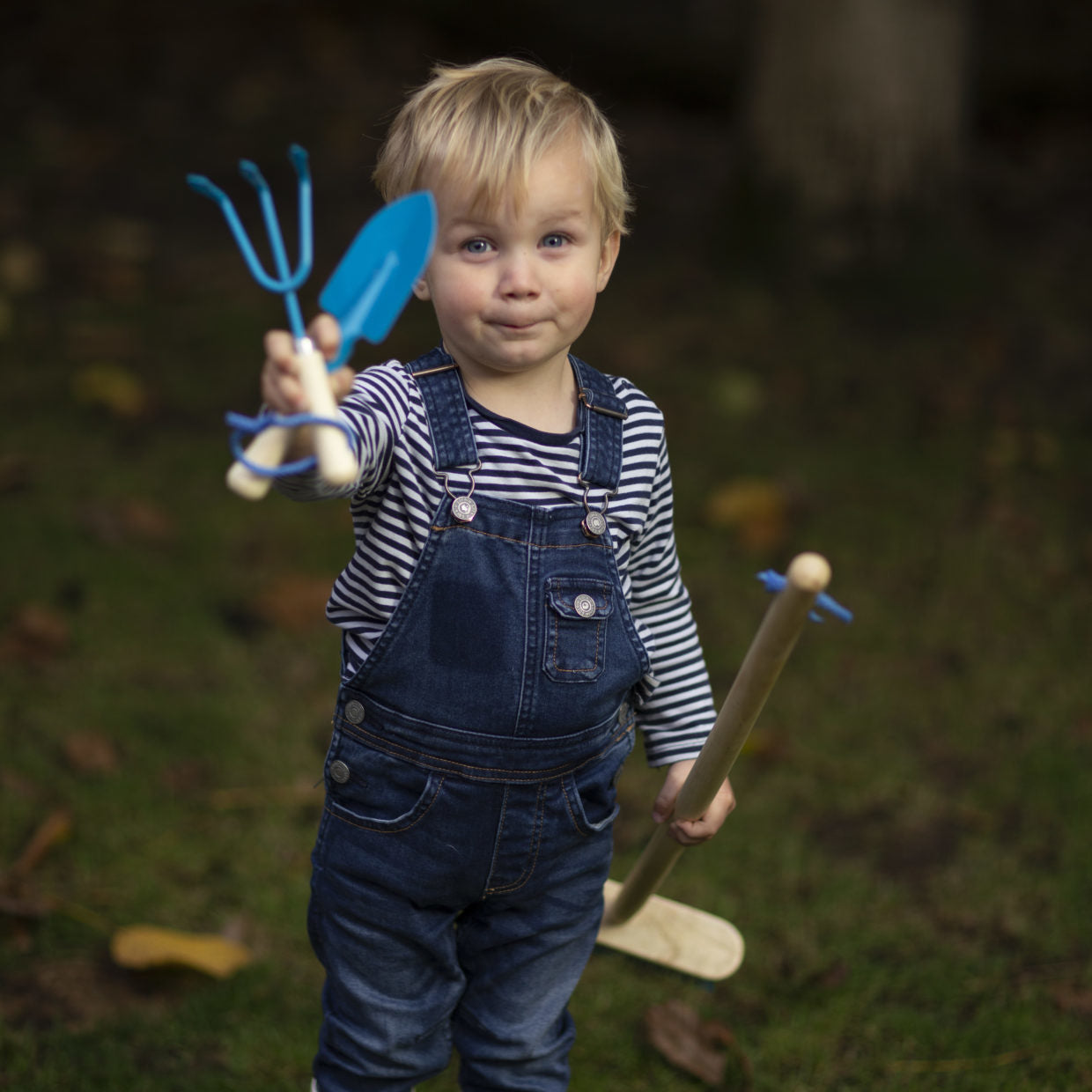 Kinderhandschep met blauwe kunststof spade en houten steel, door kind vastgehouden