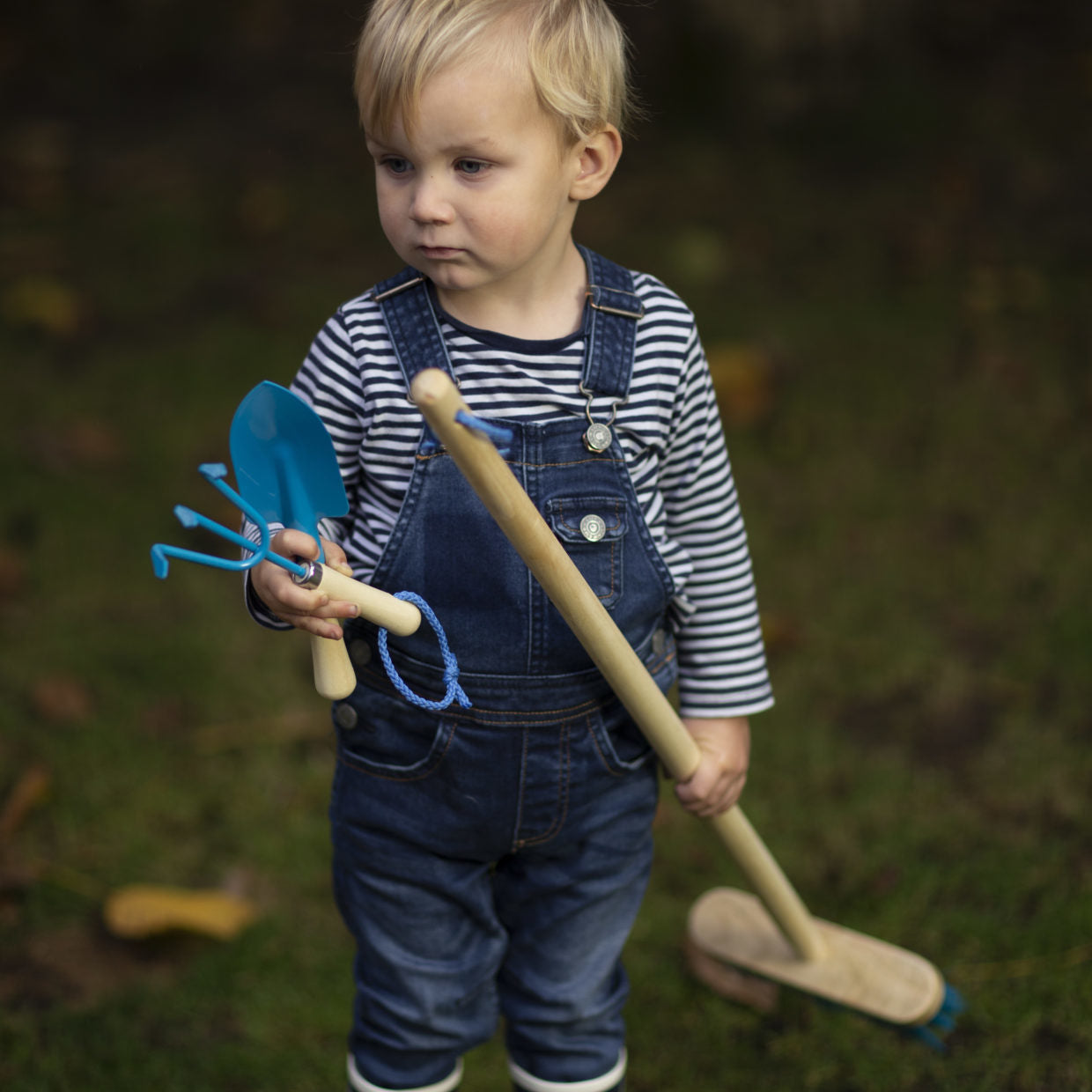 Kinderhandschep met blauwe kunststof spade en houten steel, vast in kinderhand