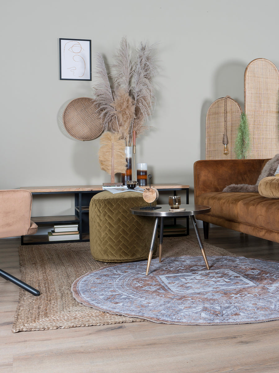 Rond vloerkleed met beige en bruin geometrisch patroon, deels zichtbaar op vloer