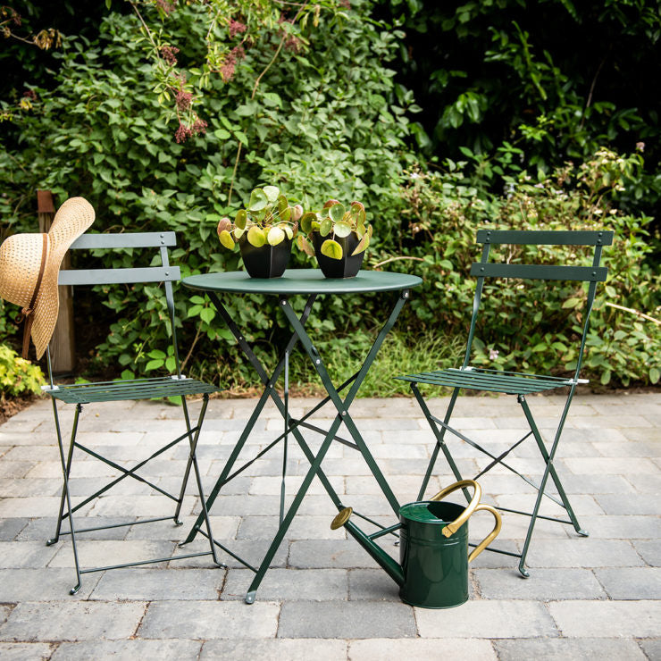 Twee groene metalen bistrostoelen met latten zitting en rug, opklapbaar frame