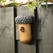 Eikel nestkastje van hout met donker textuur dak en ronde invliegopening op schutting