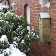 Houten vogelhuisje met ronde opening en metalen beugels