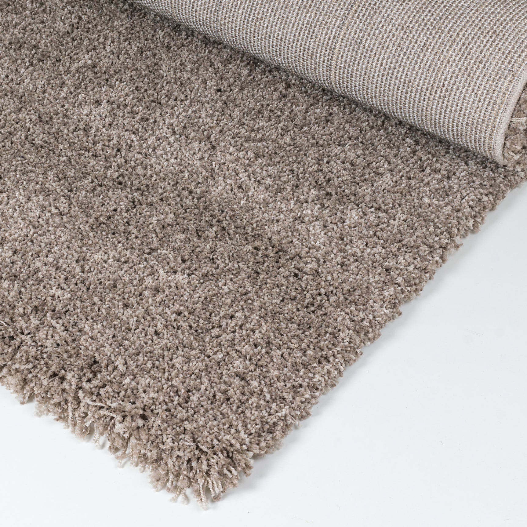 Vloerkleed met kortgeweven beige pool en franjerand aan de hoek.