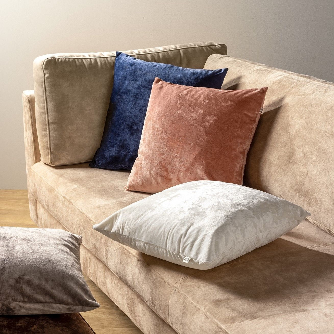 Set sierkussens op beige bank, waaronder blauw fluweel in vierkante vorm