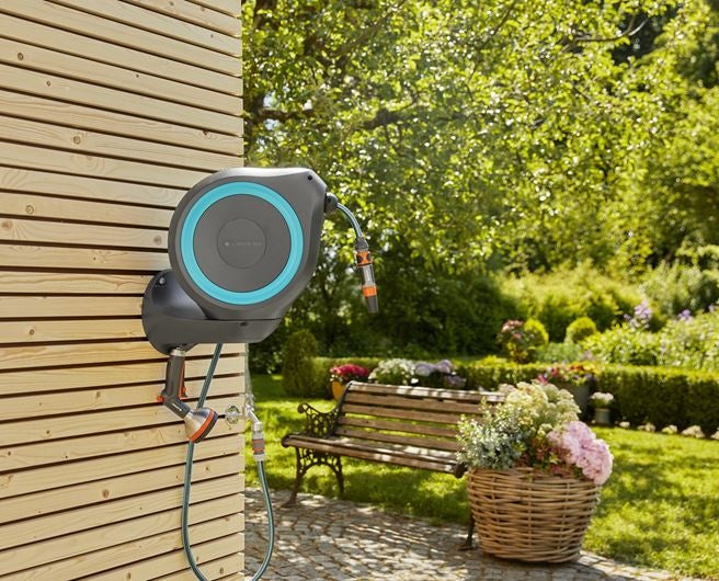 Wandslangenbox met turquoise accentring en aangesloten slang aan houten gevel