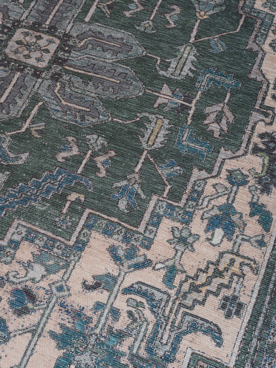Vloerkleed close-up met geometrisch patroon in donkergroen, beige en blauw met ornamentranden