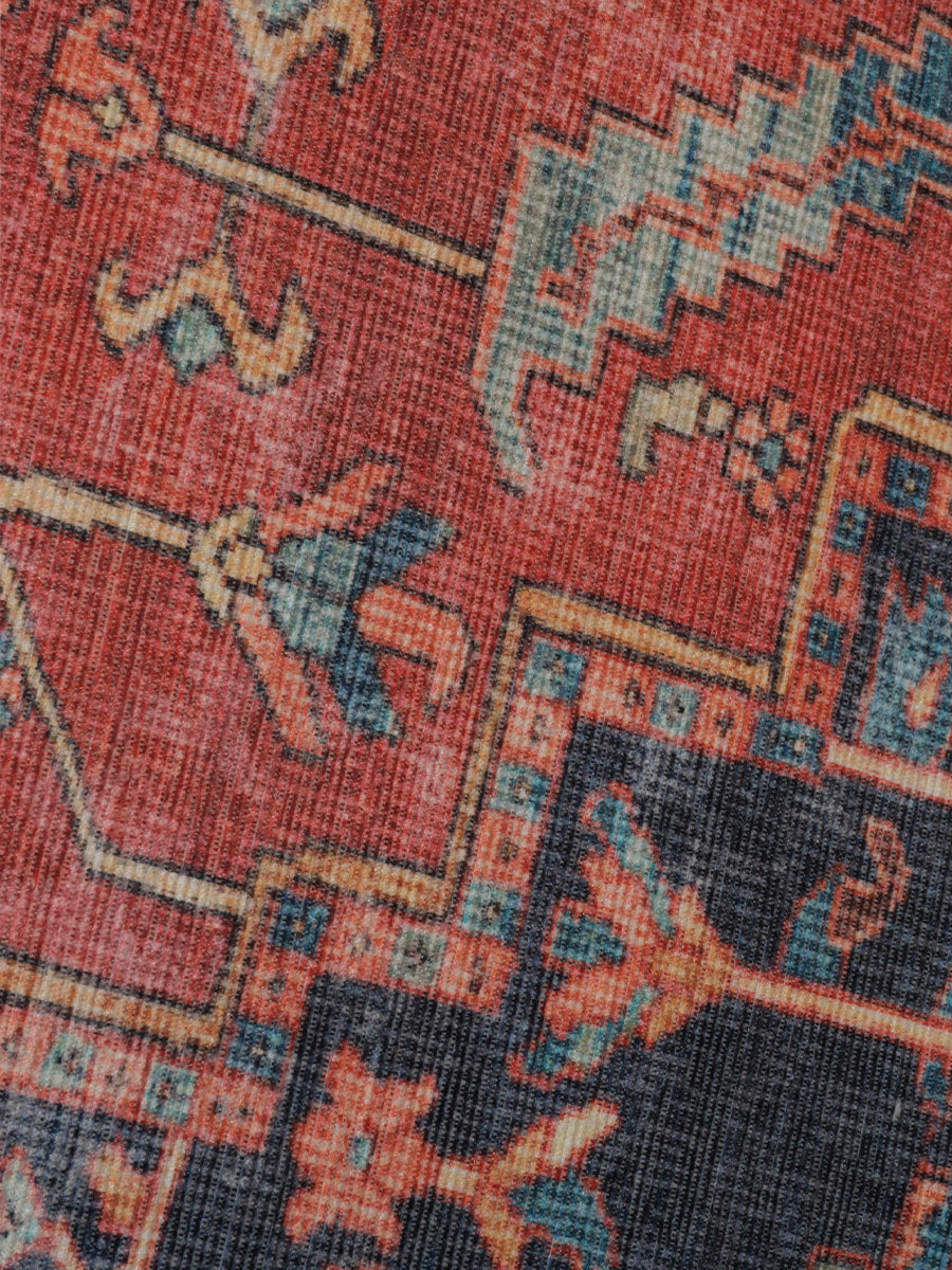 Rood vloerkleeddetail met blauw-beige geometrische patronen en poolstructuur