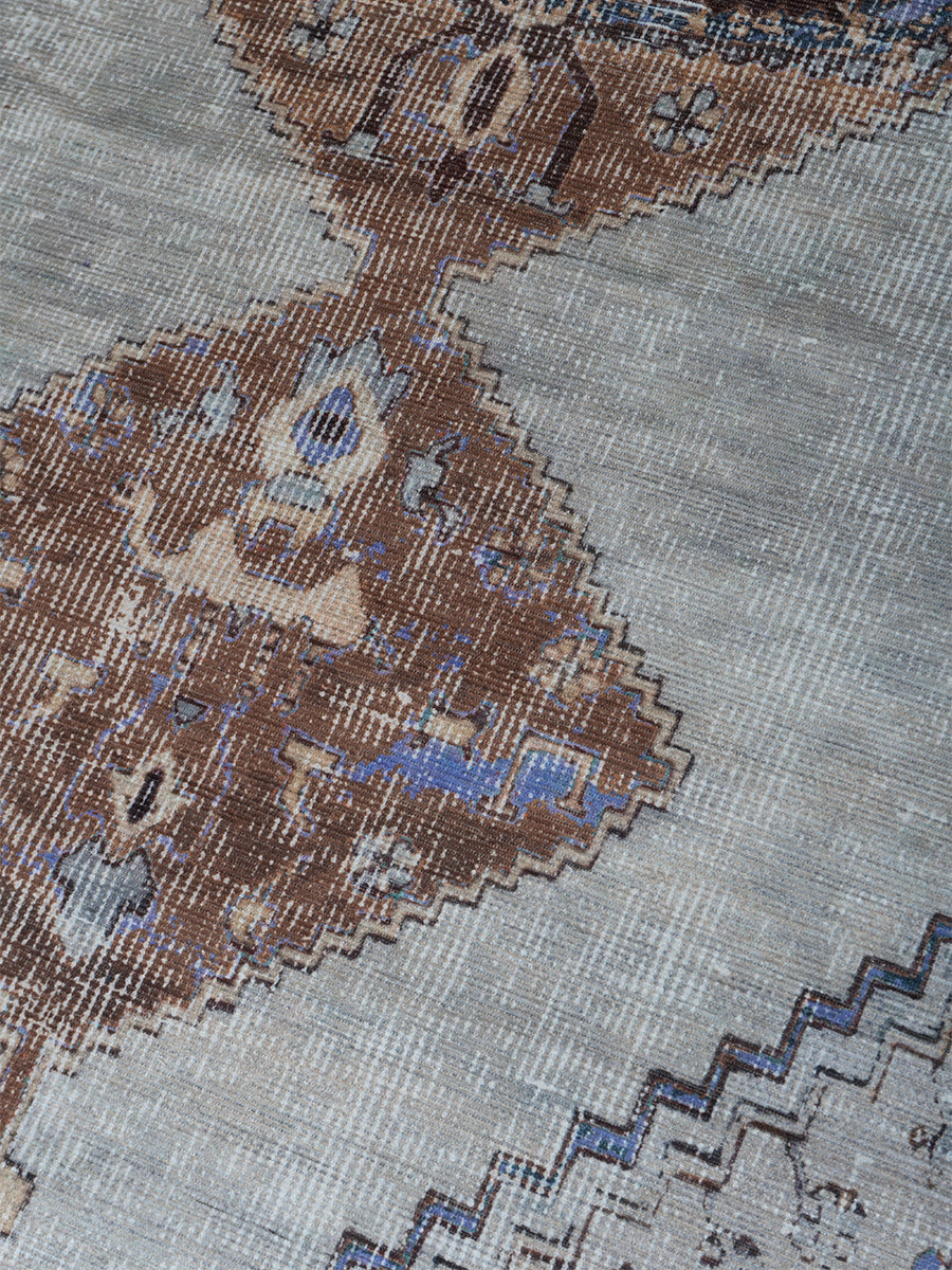 Vloerkleed detail: geweven patchwork met paars, bruin en grijs, verfijnd ornament