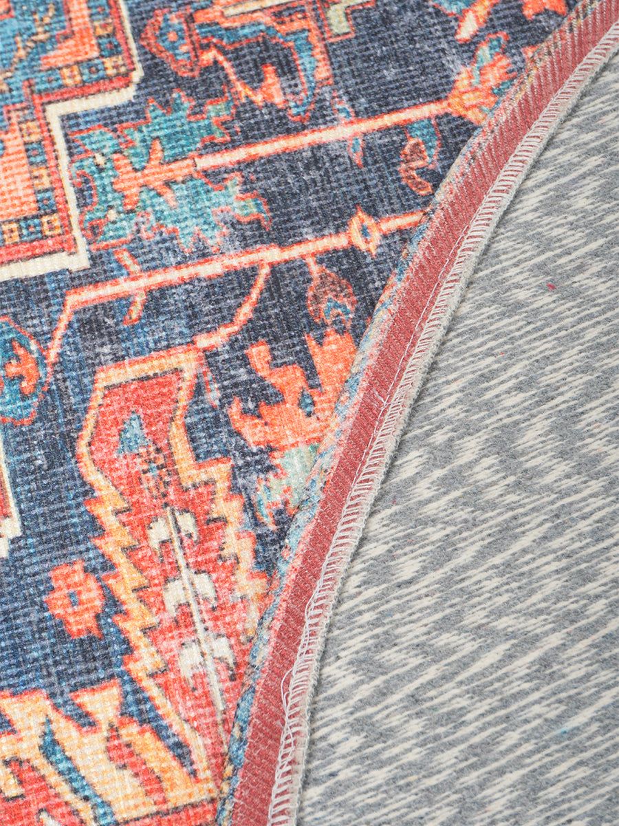 Rond vloerkleed hoekdetail met rood sierborduurwerk en blauw grafisch motief