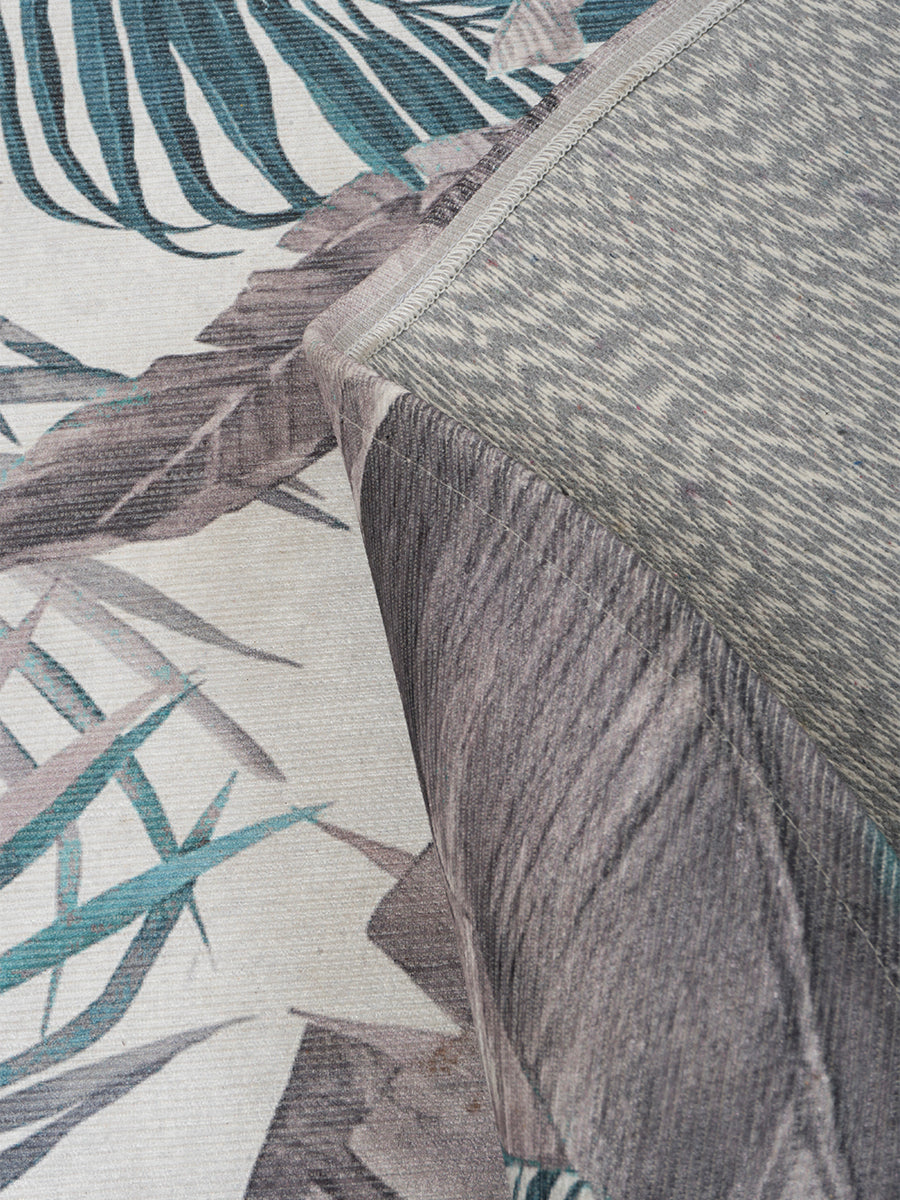 Rond vloerkleed close-up met palmbladmotief en rafelige textuur, groen-blauw/grijs