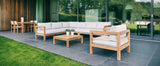 Lounge set buiten: hoekbank, twee stoelen en salontafel met lichtgrijze kussens
