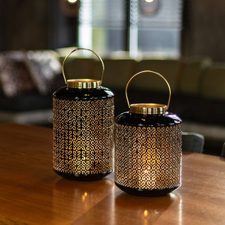 Set van twee zwarte windlichten met gouden sierraster en handgrepen.