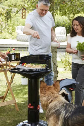 Zwarte houtskoolbarbecue met open deksel, klaar om te grillen in de tuin
