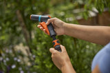 Spuitpistool met oranje trekker in hand, waterstraal gericht op groen