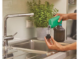 Gardena plantenspuit, zwarte fles met blauwe band en sproeikop in de hand